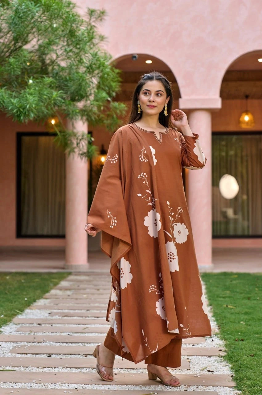 A side-angle shot of the woman looking away, highlighting the flowing silhouette of the kurta and the matching terracotta trousers. She is paired the outfit with transparent-strap block heels and traditional gold jhumka earrings.